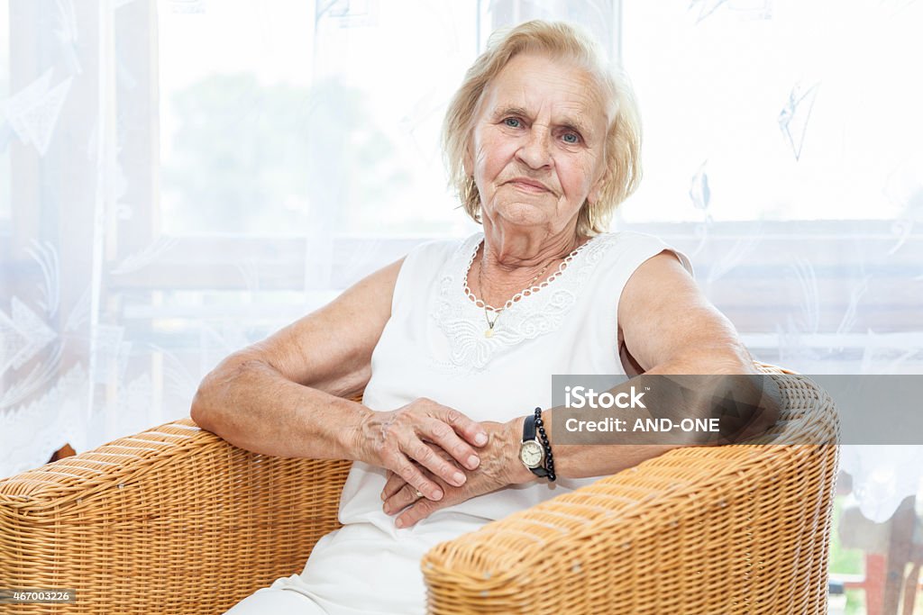 Portrait of an elderly lady sitting in a chair Portrait of an elderly lady in her 70s sitting in a chair 2015 Stock Photo