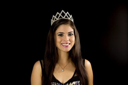Studio shot of a young lady wearing a crown simulating she is a queen or miss