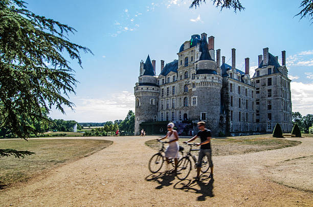 Val-de-Loire, France - August 23, 2013: Front of Brissac Castle with two cyclisst resting besides their bikes. Taken in the afternoon.