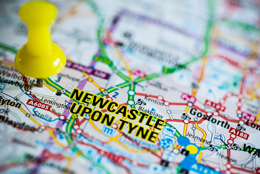 Macro image of a map showing Newcastle Upon Tyne city centre. The map is marked with a drawing pin. Narrow depth of field. Horizontal colour image with copy space. 