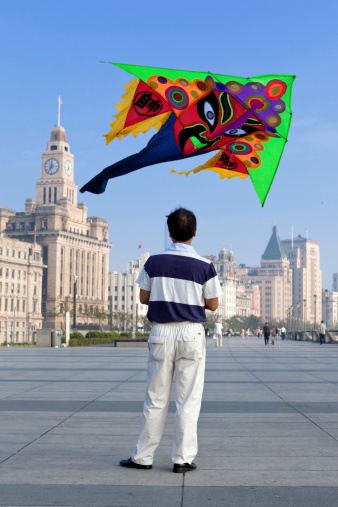 Shanghai, China - September 10, 2013: Chinese  man flying a dragon kite outdoor early in the morning near 