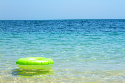 Green rubber tube floating on a clear and blue sea water.