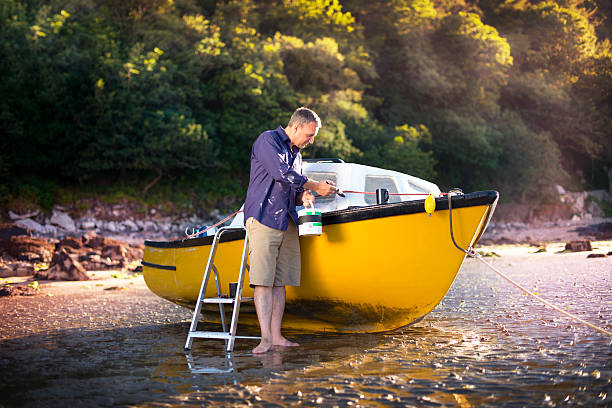 shipbuilding mature man painting a fixer upper of a boat motorboat maintenance stock pictures, royalty-free photos & images