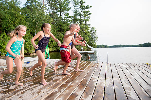 2 young boys and a young girl are jumping into a lake.  They have very happy faces and show alot of excitement