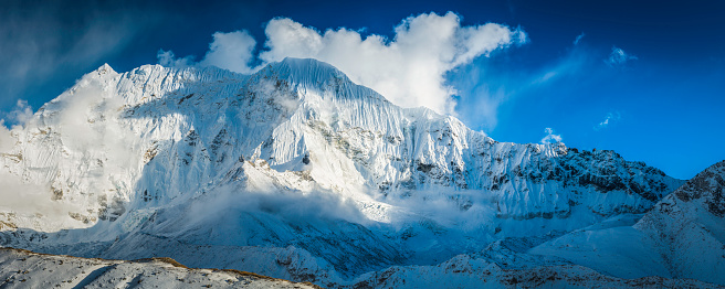 Sunlight and shadows on the crisp white fluted snow, dramatic rocky ridges and hanging glaciers of the remote Himalaya mountain peaks of Amphulapcha (5663m) deep in the Everest National Park of Nepal, a UNESCO World Heritage Site. ProPhoto RGB profile for maximum color fidelity and gamut.