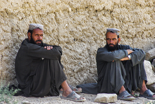 Kaboul, Afghanistan - August 20, 2010: The picture was took in the capital of Afghanistan during a morning time, we can see a portrait of two Afghan men,dressed in traditional clothing, they are waiting, arms crossed with wary look. August 2010