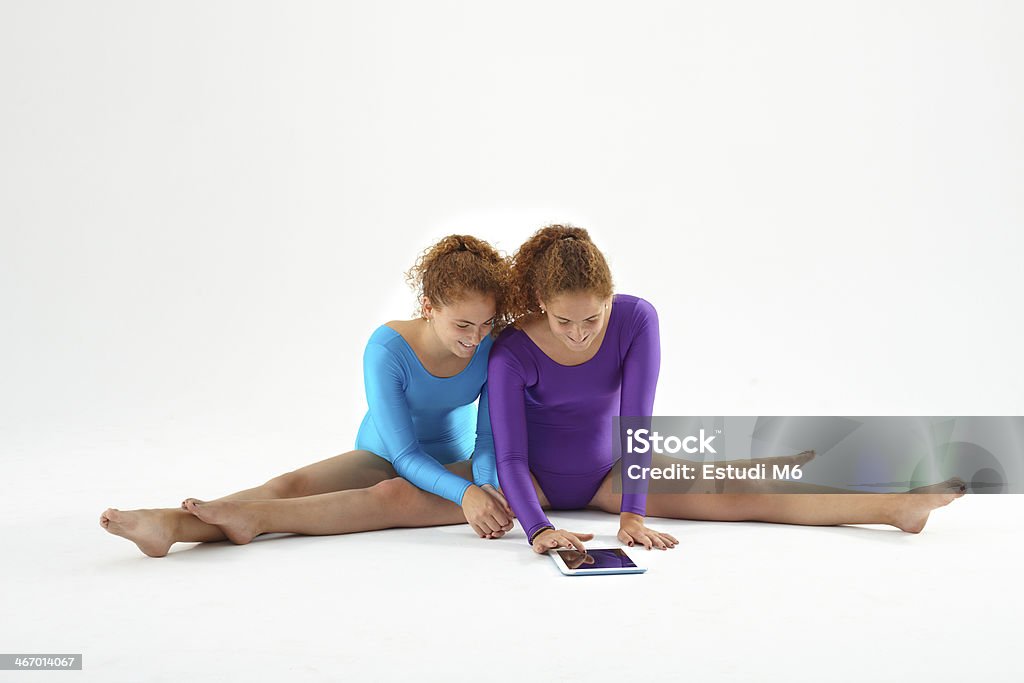 Twin sisters with digital tablet Twins sisters looking at digital tablet while practicing gymnastics 16-17 Years Stock Photo