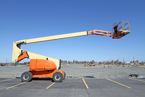 Mobile boom lift equipped with a work platform, commonly seen on construction sites and for building maintenance.