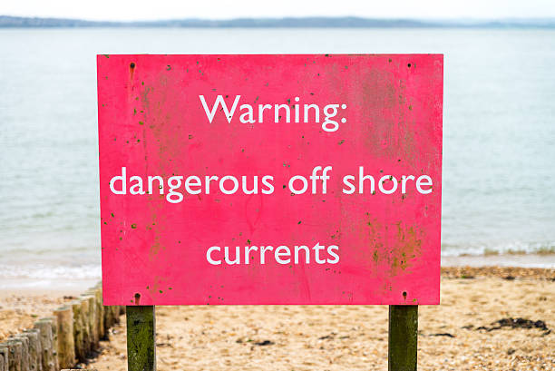 Beach sign warning of dangerous off shore currents stock photo