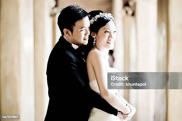 An Asian Couple In Wedding Attire Smile And Embrace Stock Photo - Download Image Now