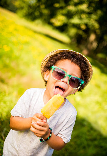 Kid licking ice cream on sunny summer day Little boy with sunglasses, hat and curly hair licking ice cream licking ice cream cone stock pictures, royalty-free photos & images