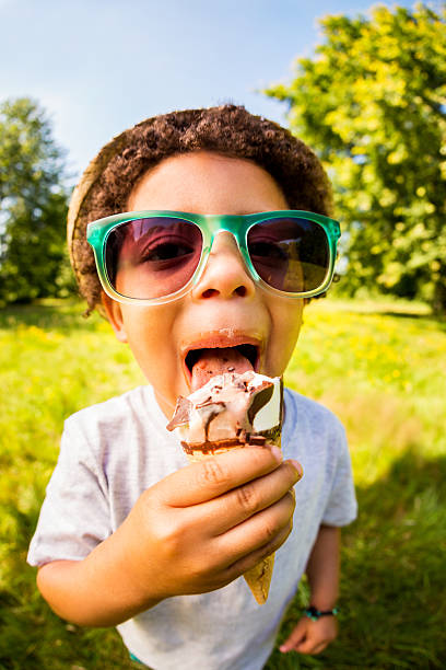 junge mit sonnenbrille lecken chocolate ice cream - child chocolate ice cream human mouth stock-fotos und bilder