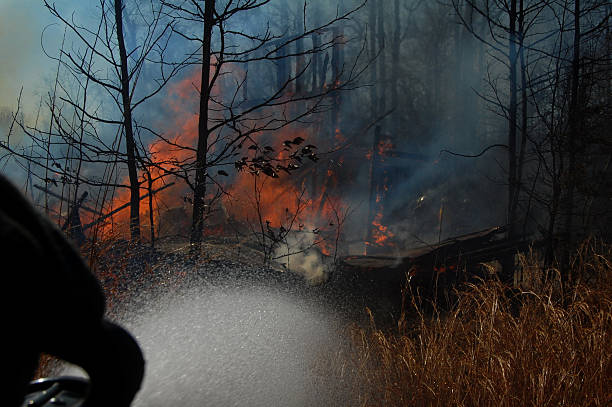 istock Fire hose spraying water with fire in background 467033464