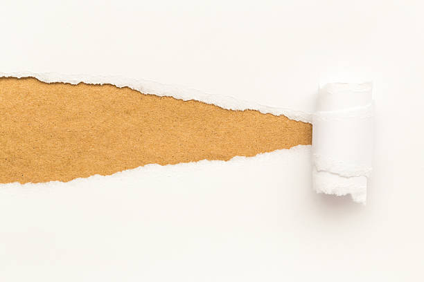 istock Torn white paper curling up to reveal brown cardboard 467036730