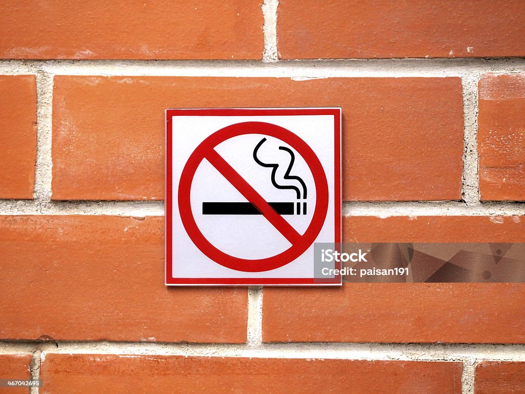 Sign hangs on a brick wall warning Sign hangs on a brick wall warning that smoking is not permitted in the area Brick Stock Photo