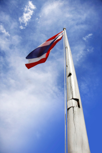 old flag of thailand holding up to beautiful blue sky with cloud