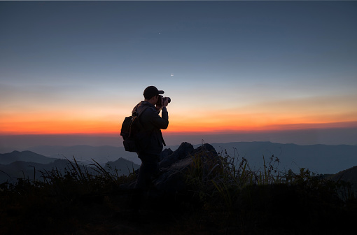 Silhouette of a photographer with his camera on a hilltop, chiangrai province, thailand
