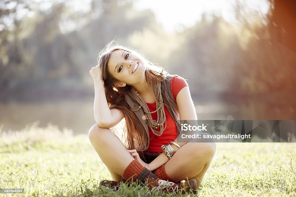 girl on grass young woman sitting on grass with legs crossed looking at camera Adult Stock Photo