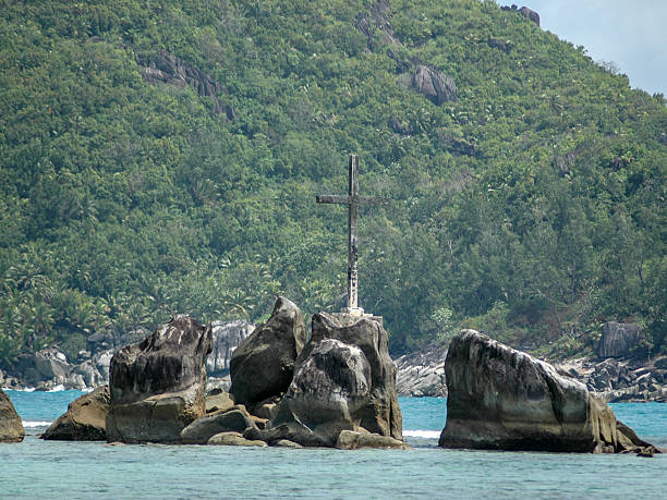 Mahe, Seychelles - July 16, 2007: A delapidated wooden cross stands proud on an isolated rocky outcrop in the Baie Ternay Marine National Park, Mahe, Seychelles