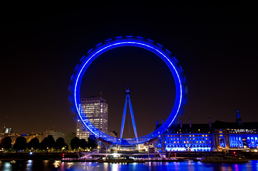 London, United Kingdom - October 16, 2013: London Eye spinning in the evening with reflection in the Thames