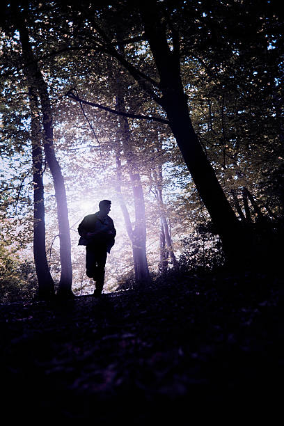 Silhouette of a man running away, escaping in a forest.