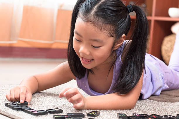 Cute little girl playing domino on floor. stock photo