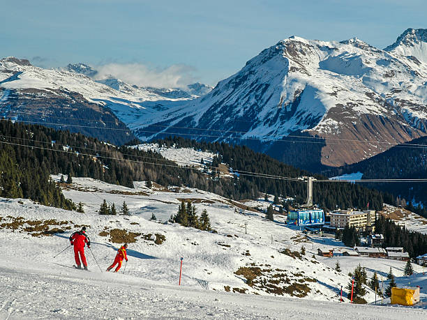 Weisshorn Panorama Arosa, Switzerland - December 31, 2006: Weisshorn Panorama. Two brightly coloured skiers make their way down the valley towards Arosa in the foreground. A cable car makes its way up to the mittelstation against a mountain backdrop. Arosa, Switzerland. arosa stock pictures, royalty-free photos & images