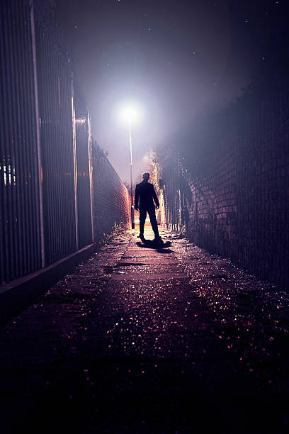 The silhouette of man standing in dark alley. stock photo