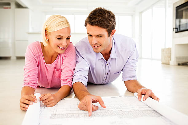 istock Man Discussing Blueprint Plan With Woman At Home 467070389