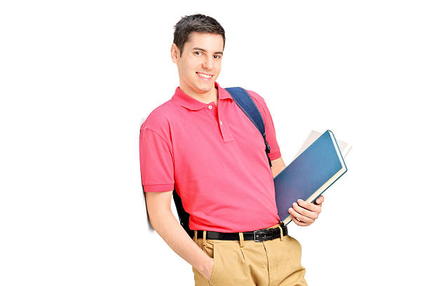 istock Smiling student holding books and leaning against wall 467073201