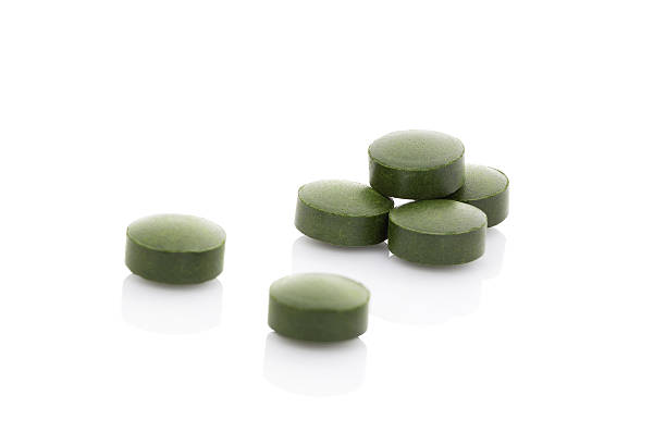 Spirulina in pills on whole background, close up