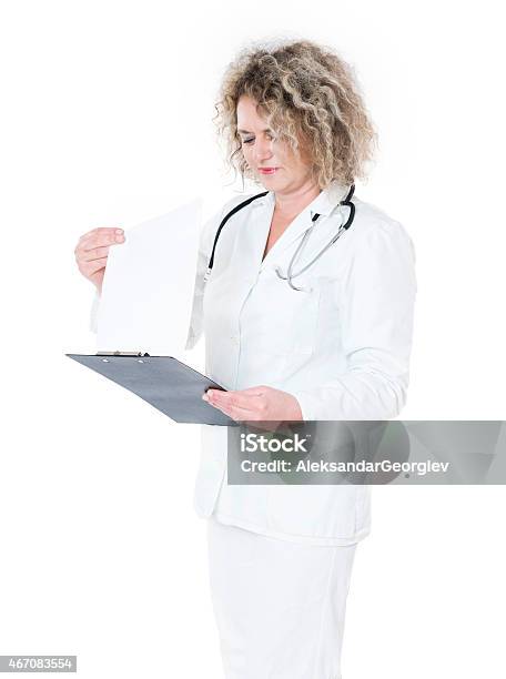 Mature Female Doctor Writing Reading Notes And Working In Uniform Stock Photo - Download Image Now