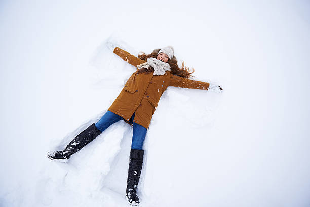 It's the perfect snow angle High angle shot of a young woman making a snow angel snow angels stock pictures, royalty-free photos & images