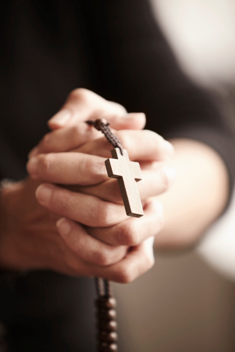 Hands clasped and holding a Rosary in prayer