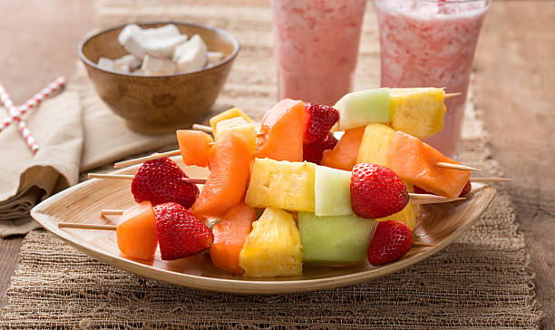 Strawberry smoothies and a bowl holding several fruit kabobs stock photo