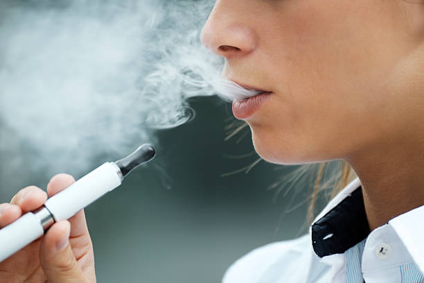 closeup of woman smoking electronic cigarette outdoor - vape stockfoto's en -beelden