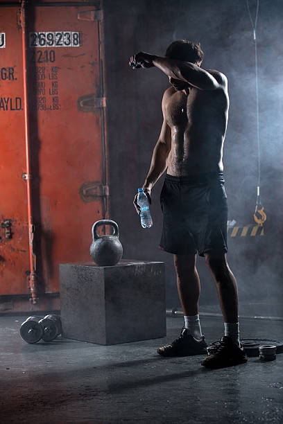Tired athlete topless wipes the sweat from his forehead stock photo