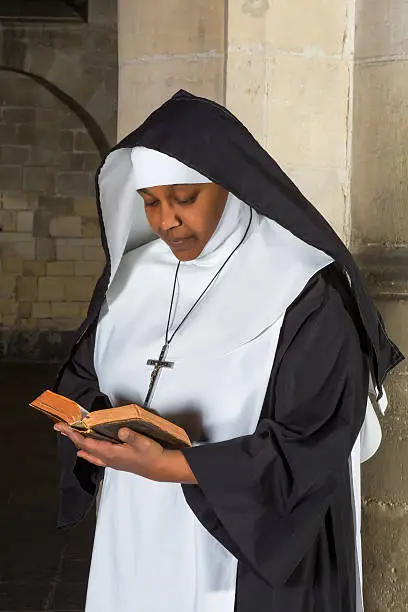 Mature nun reading the bible in a medieval church
