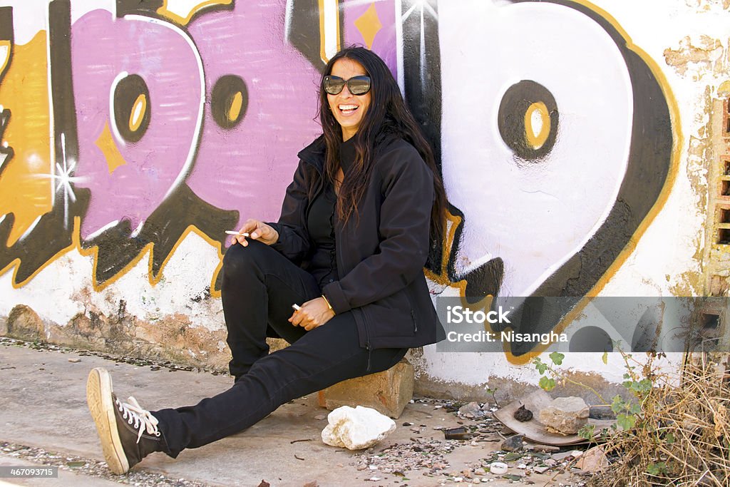 Fumantes mulher feliz na frente de uma parede de graffiti - Foto de stock de Adulto royalty-free