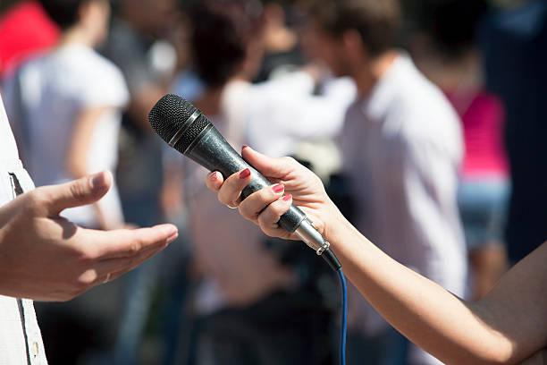 istock Woman holding a microphone and interviewing a man 467095179