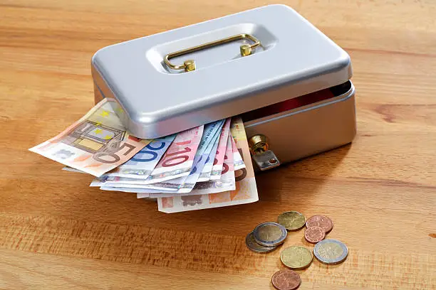 Cash box with euro notes and coins on wood