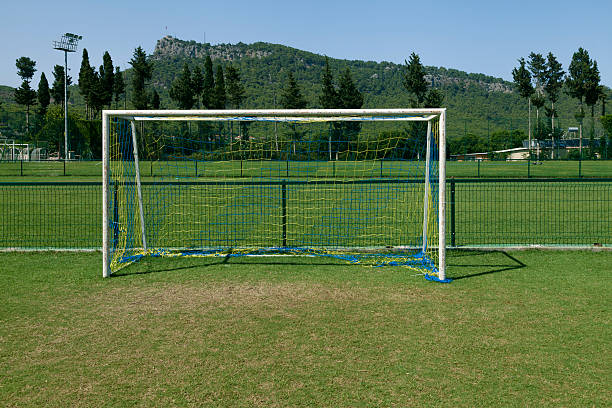 football goal keep castle with white goalposts and colorful goal net on grass football area against nature background