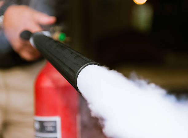 Fire extinguisher being used indoors Close up taken as a man fires a carbon dioxide fire extinguisher. fire extinguisher photos stock pictures, royalty-free photos & images