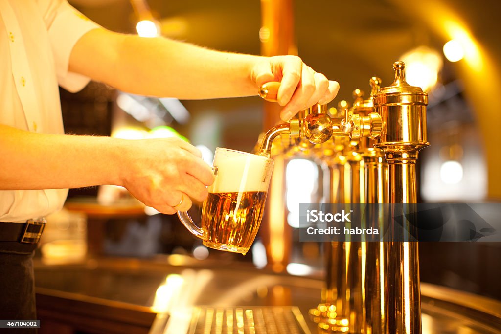 Bartender filling a beer mug from the tap gold beer in the hand and beer tapsgold beer in the hand and beer taps 2015 Stock Photo