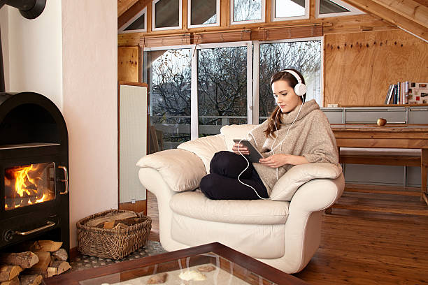 jovem mulher em casa na cadeira com tablet - log fire audio - fotografias e filmes do acervo