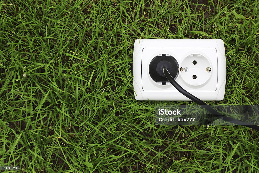 Presa di alimentazione elettrica su uno sfondo di erba verde - Foto stock royalty-free di Ambiente
