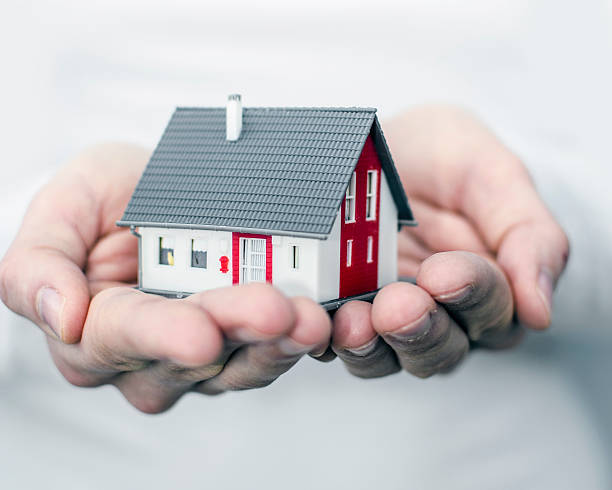 istock Close-up of human hands holding a model home 467119671