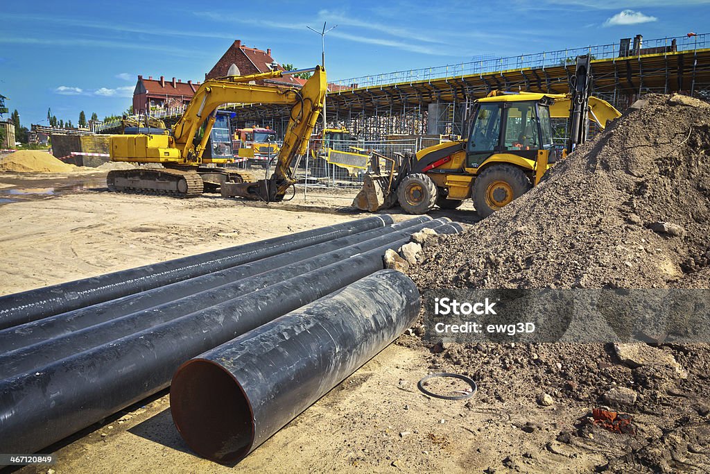 New highway viaduct under construction Summer scene with a black steel pipes, construction machinery and highway viaduct under construction Backhoe Stock Photo