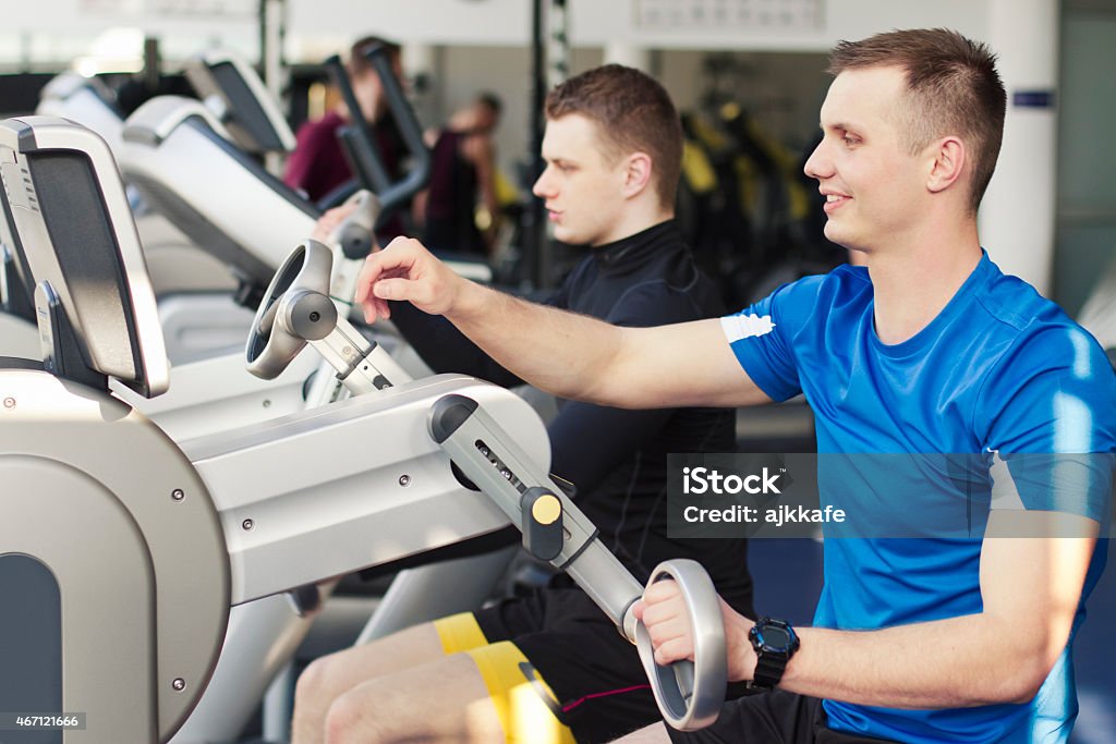 Young people in gym using arms training machine Group of young people in a gym, exercising with arms training machine. 20-29 Years Stock Photo