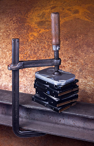 istock heavy screw clamp giving pressure to several hard drives 467126855